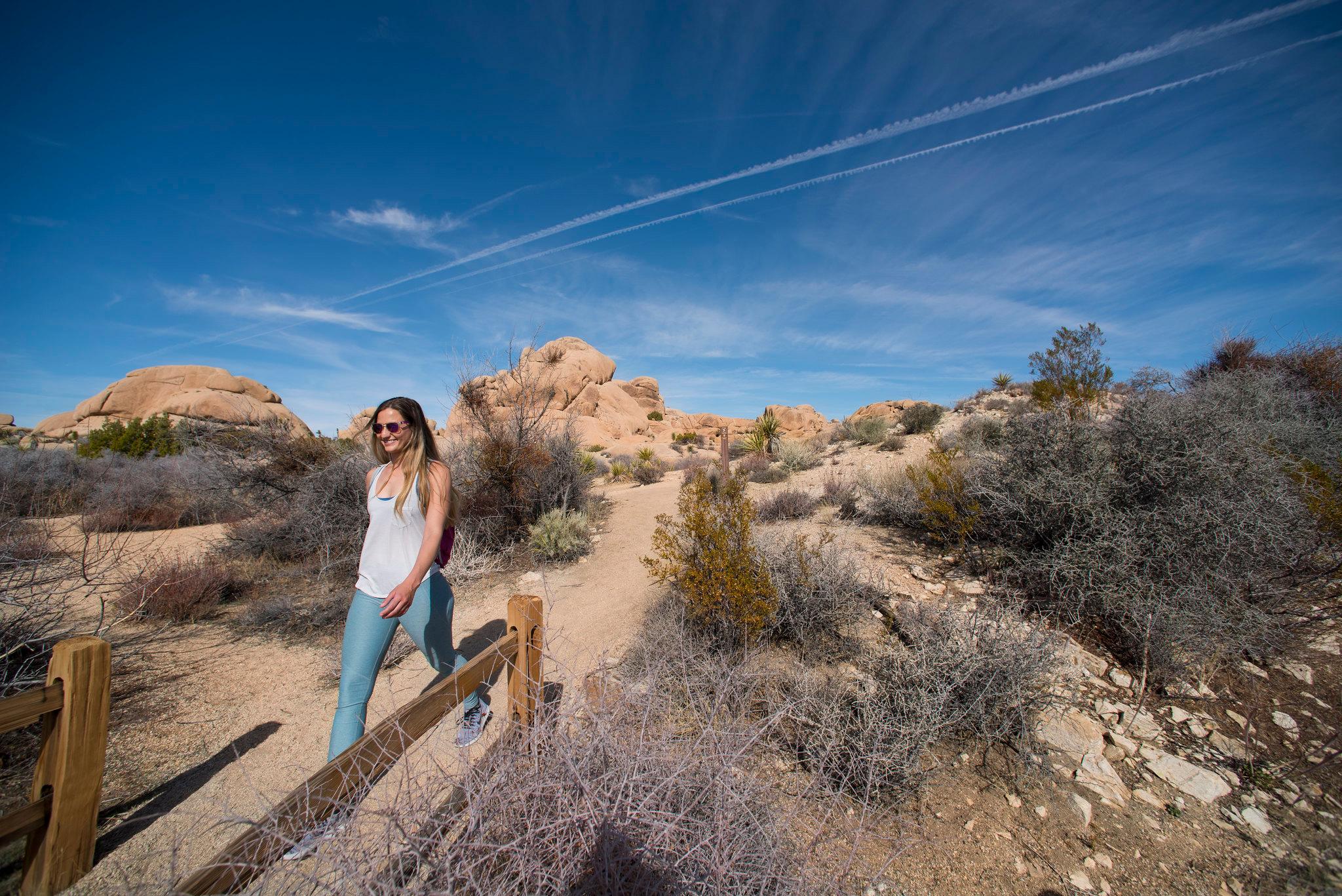 A hiker walking on a dirt trail with rocks in the background
