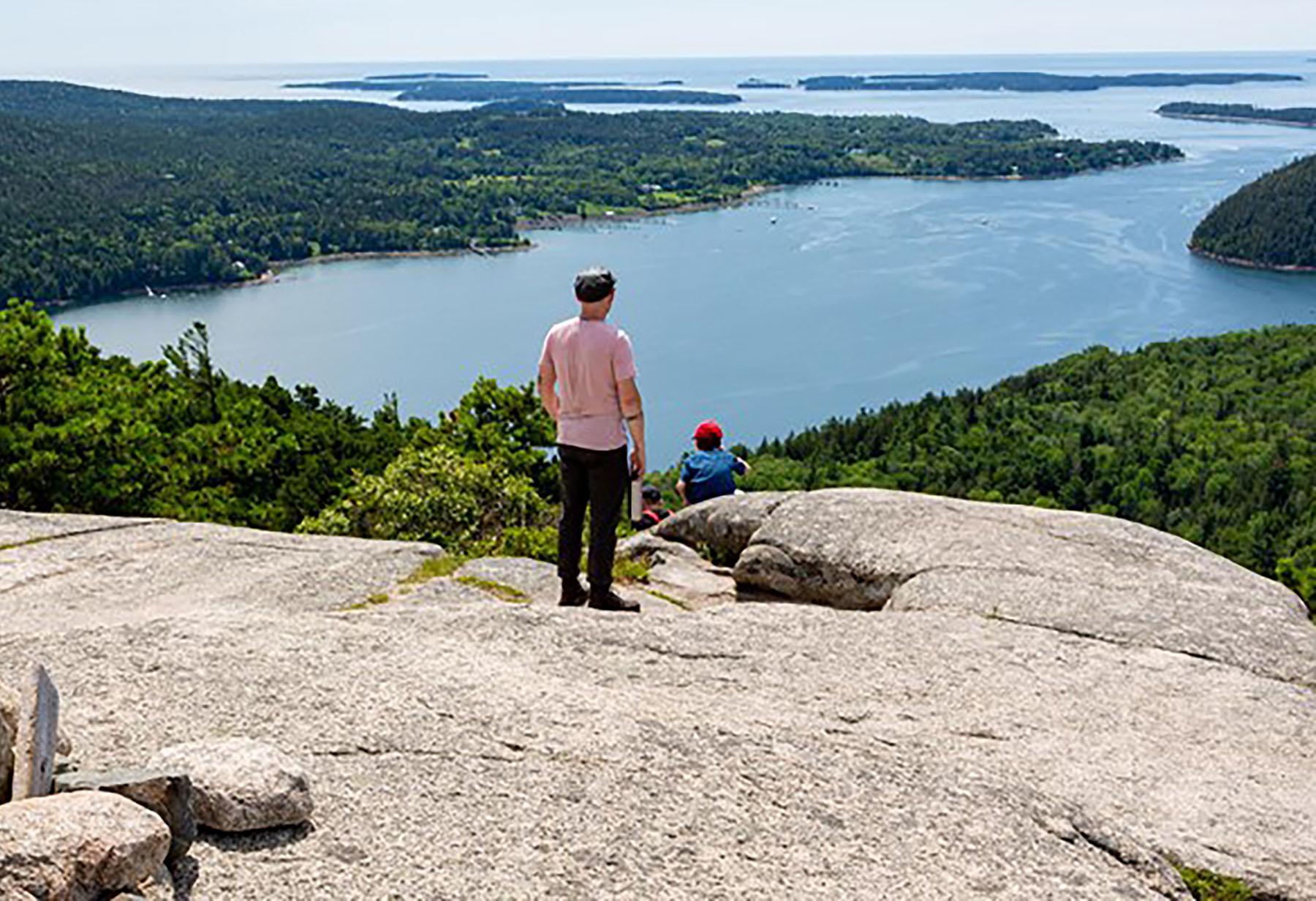 Visitors overlook islands from a mountain summit.