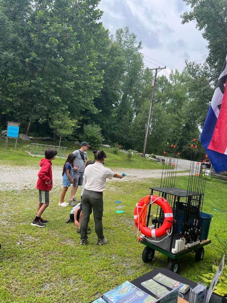 Intern demonstrates how to cast fishing rod to group of visitors