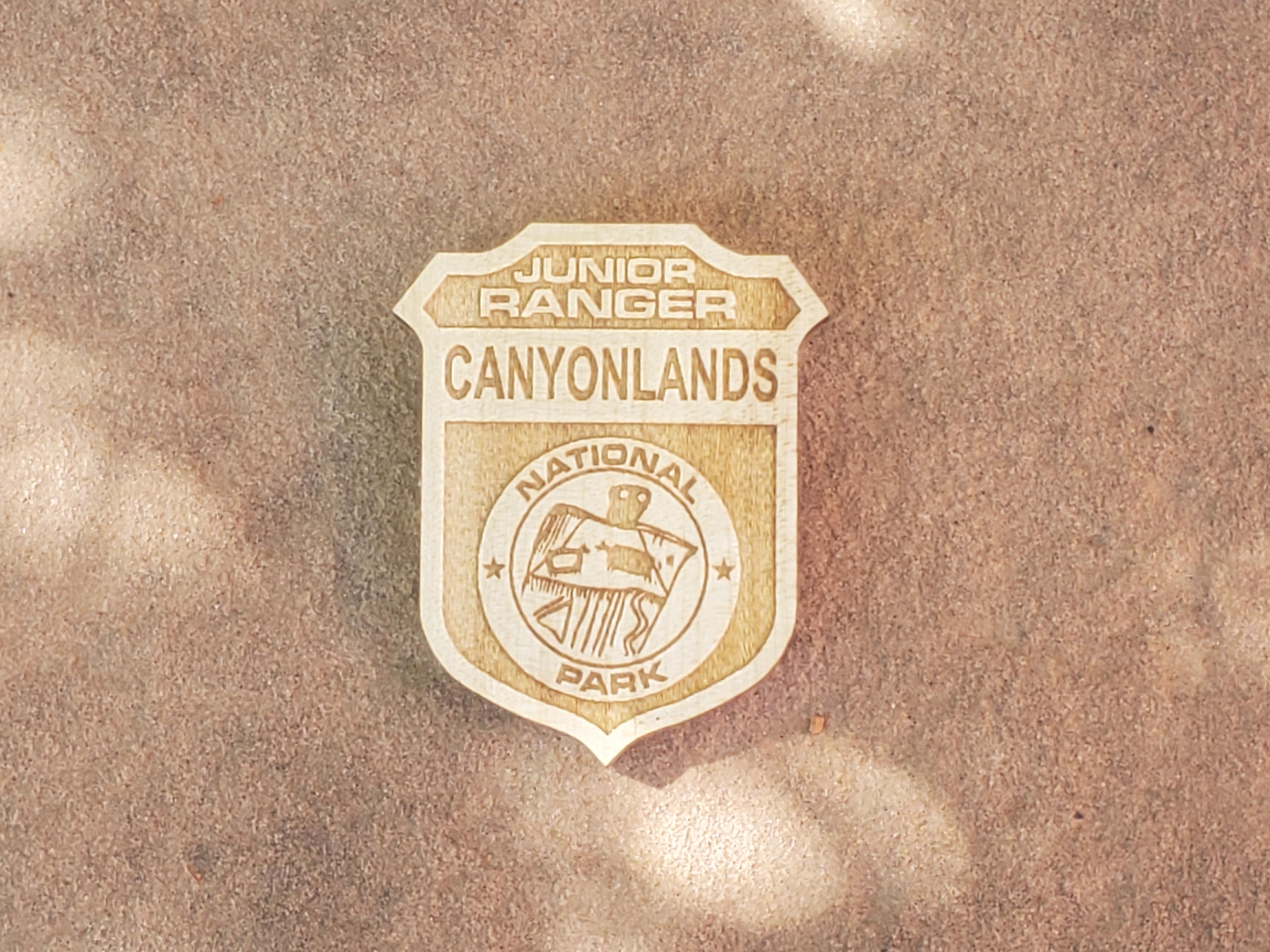 wooden badge with "Junior Ranger Canyonlands" and a drawingin a circle