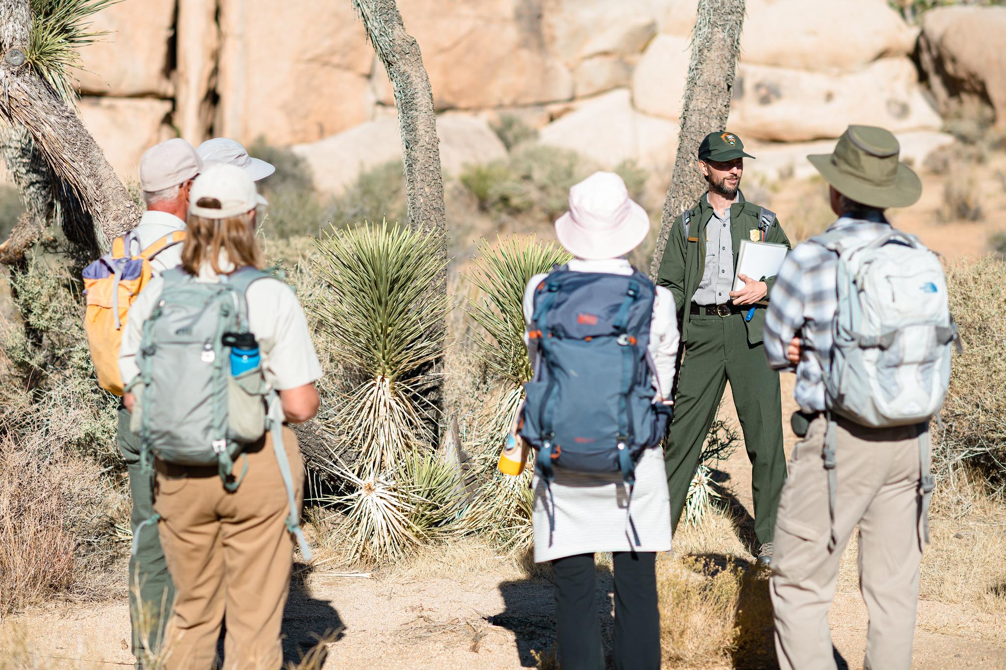 A uniformed ranger presents a program about Joshua trees along the Cap Rock Nature trail